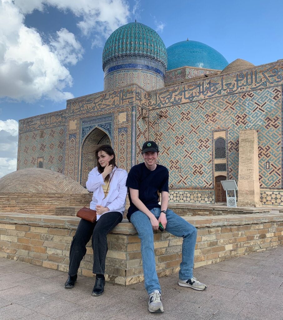 Two students sit in front of a mosque in Kazakhstan.